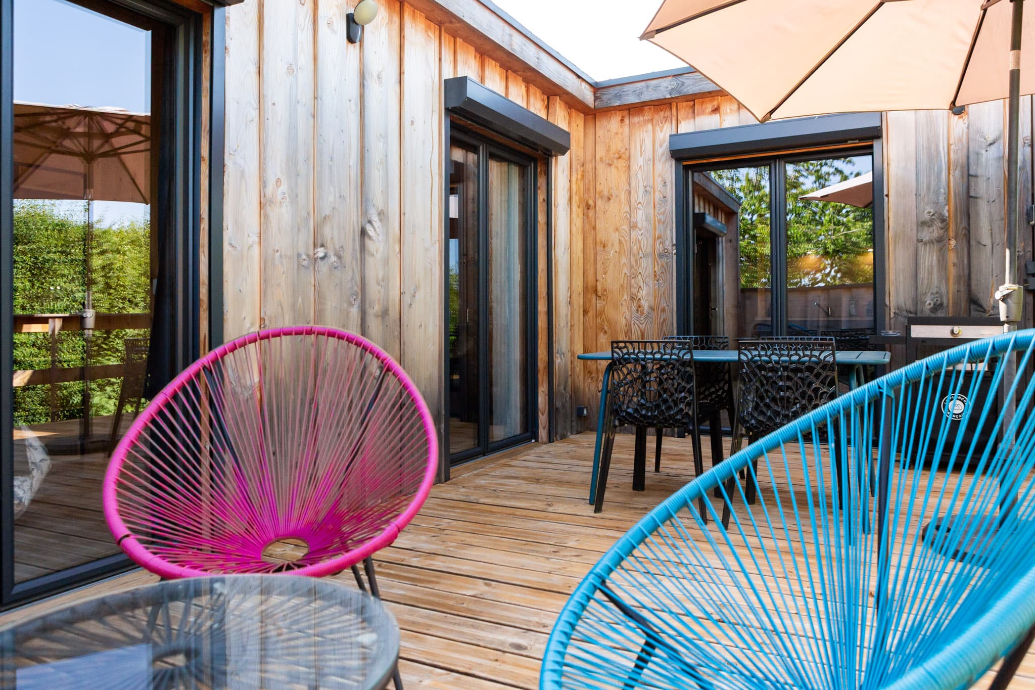 Transats et fauteuils de détente sur la terrasse du gîte au cœur du verger